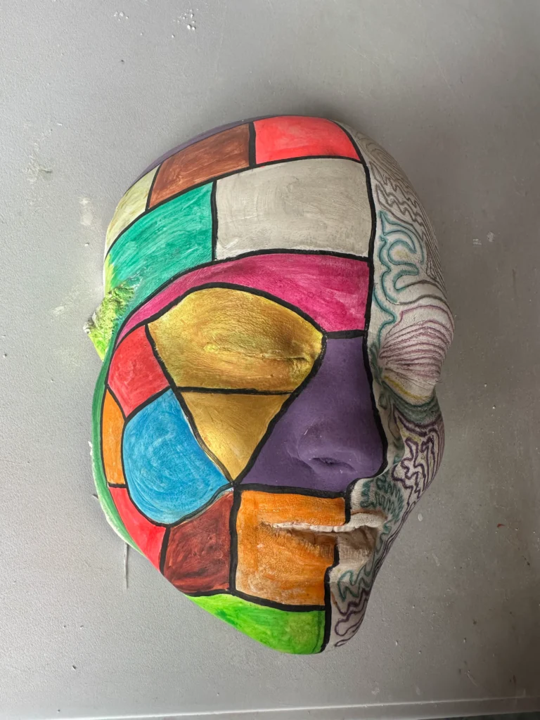 sculpture of face that has been painted in variable colours