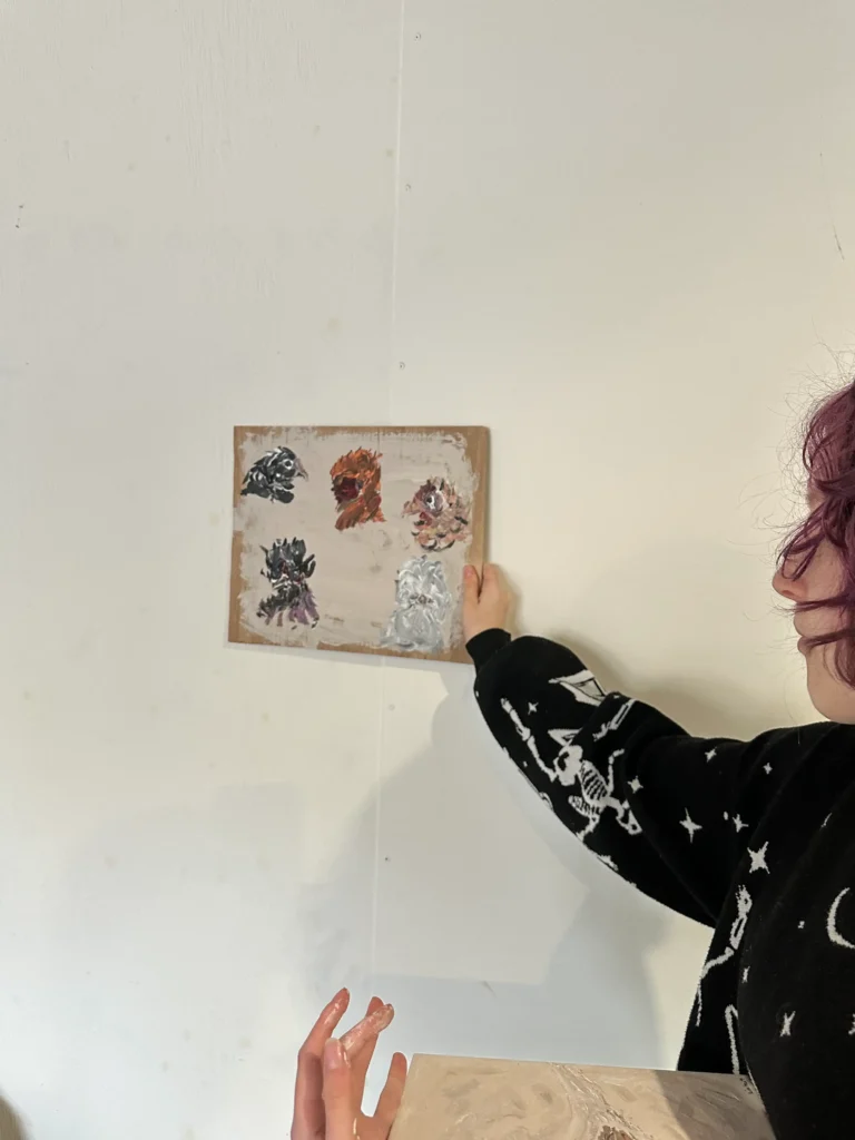student holding up their work toward the wall to show the camera