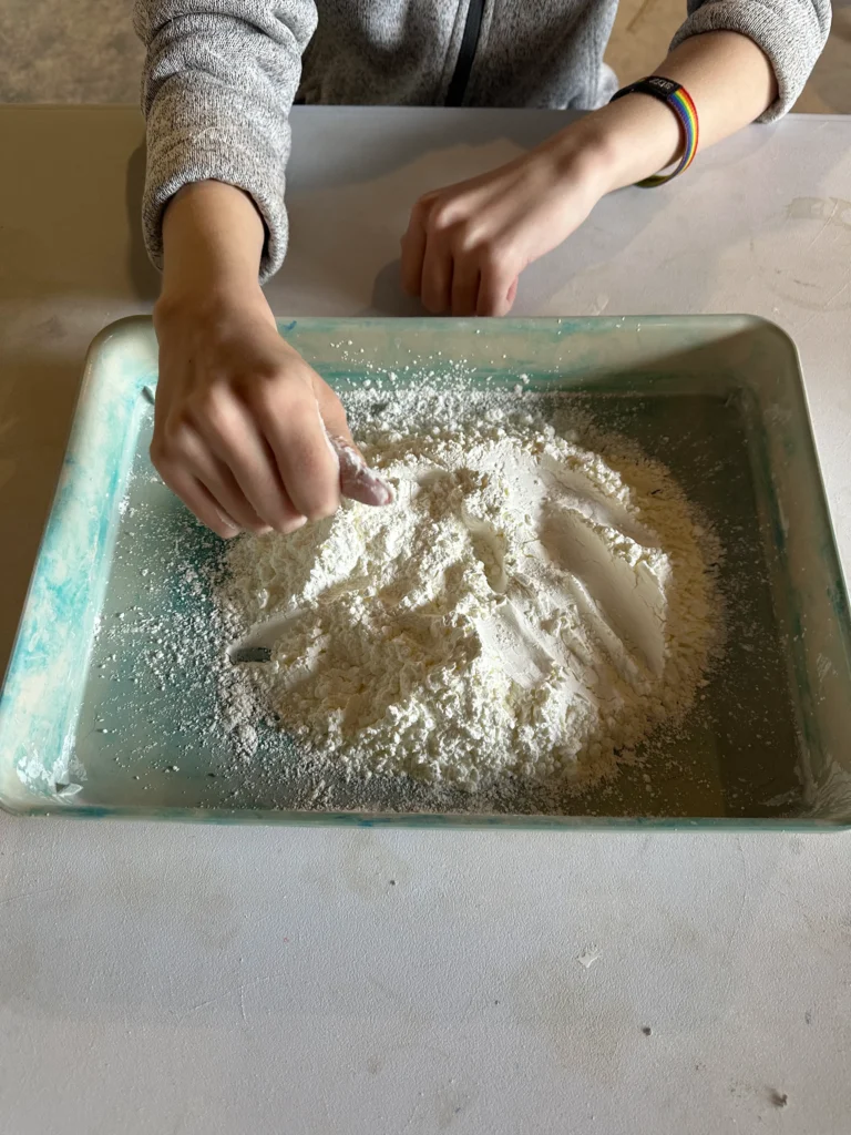students mixing sand in a tray on the table