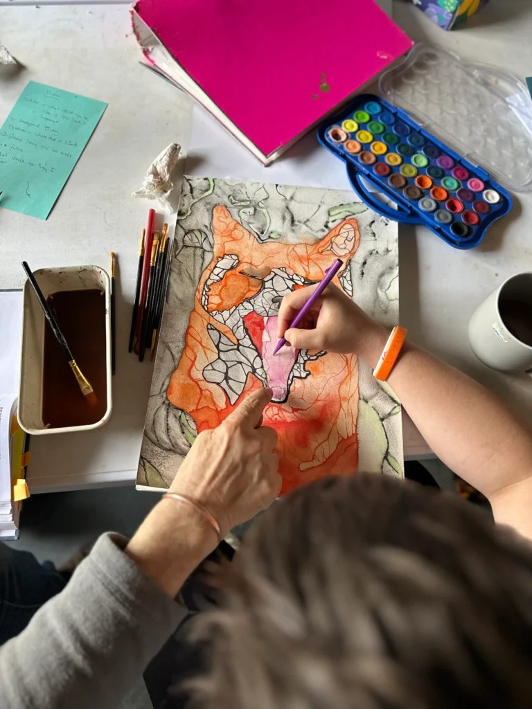 student drawing being supported by teacher